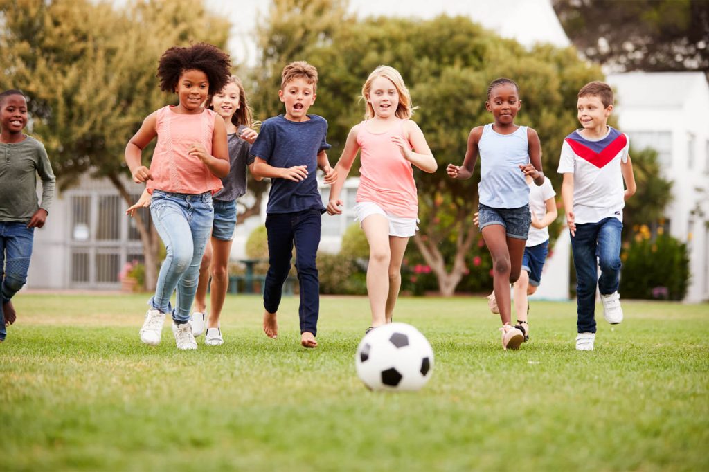 a group of children running toward a soccer ball