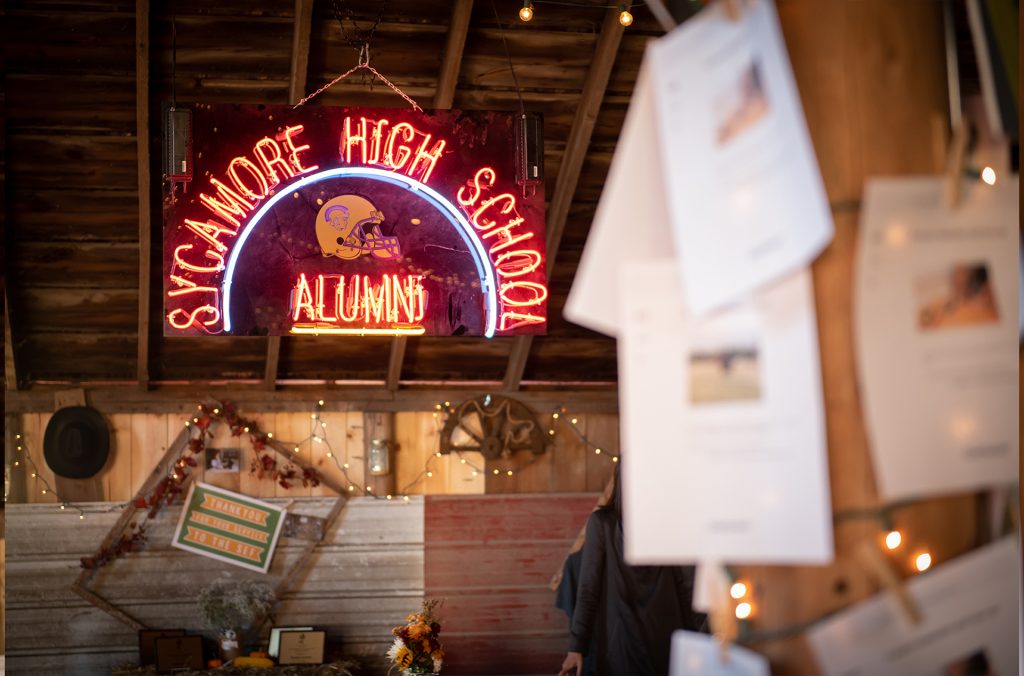 an LED sign that says sycamore high school alumni with a foot ball helmet at the center of the sign