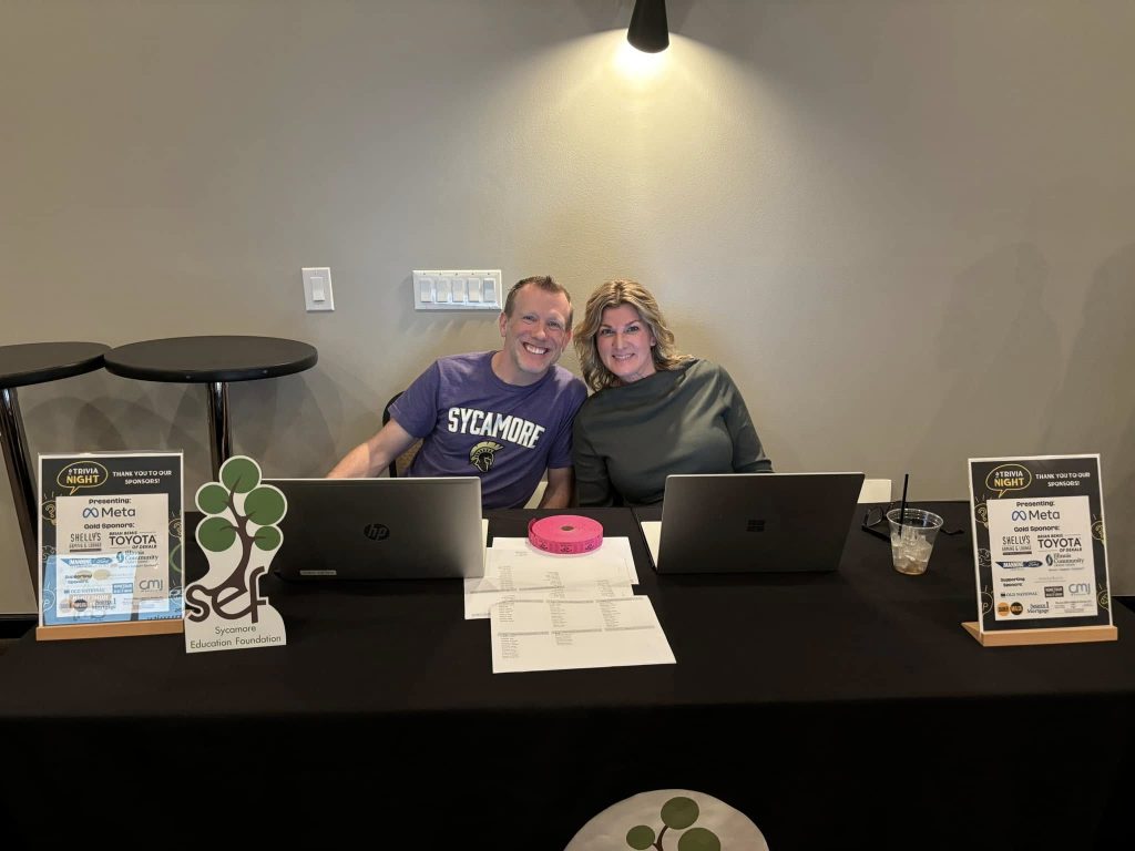 Two people sitting behind computers smiling