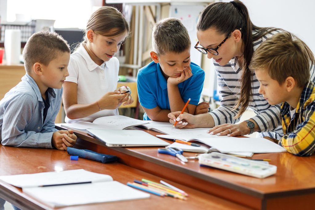 a group of kids and an adult stand around a pile of books